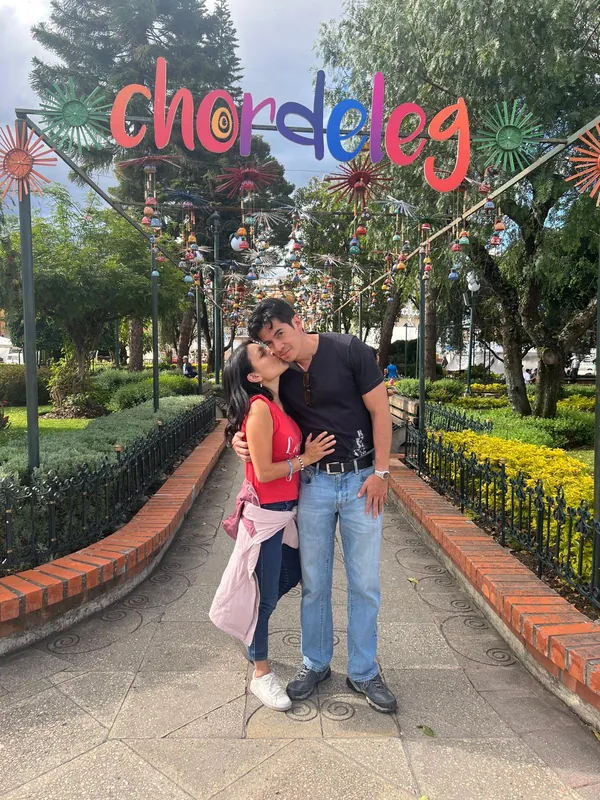 A couple posing under the colorful Chordeleg town sign